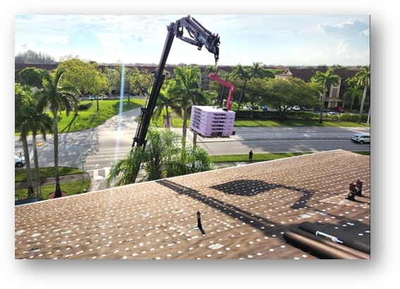 Crane lifting shingle bundles onto large condo roof – Job 22-071-F