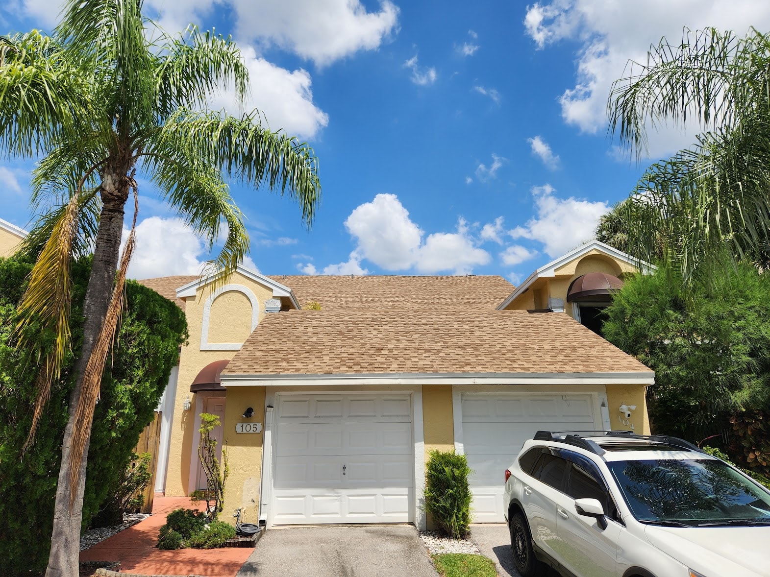 Completed tan shingle condo roof with palm trees – Job 23-010