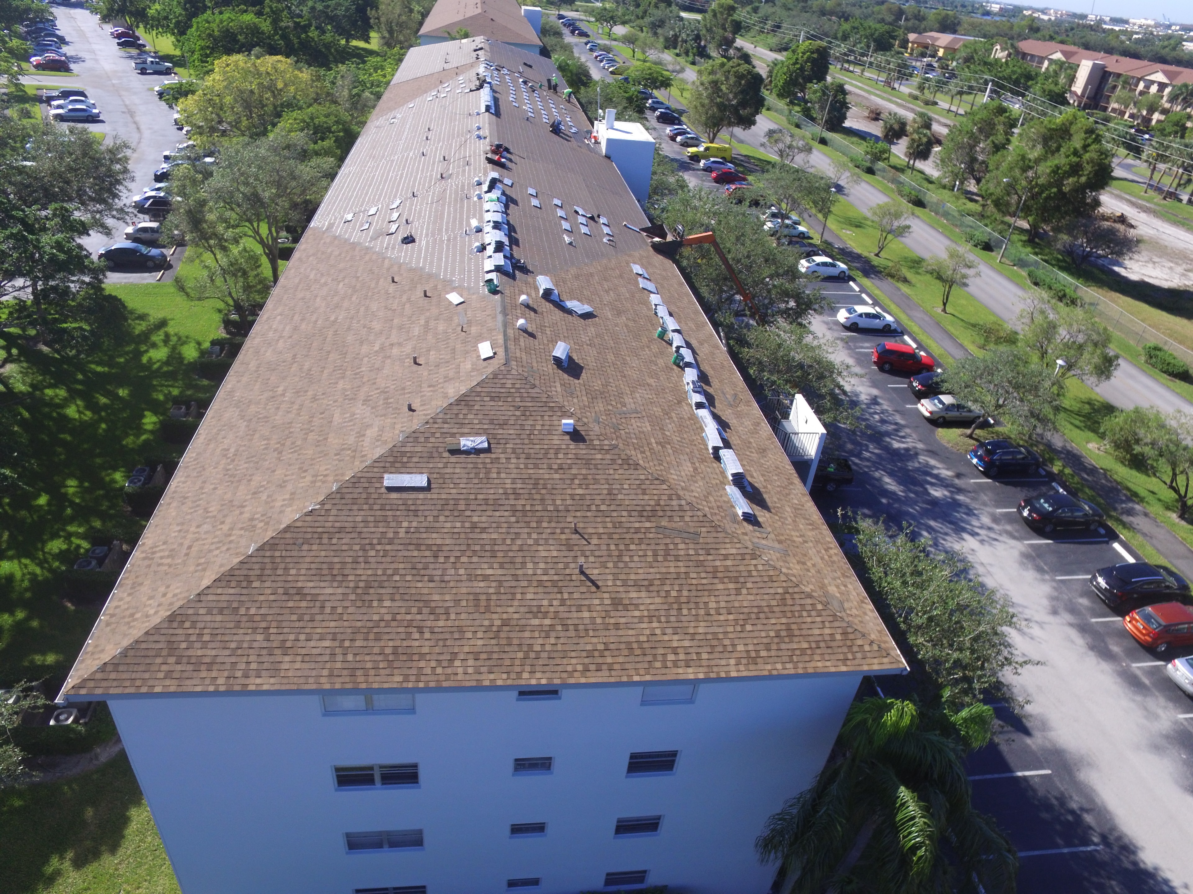 Aerial view of Century Village Ivanhoe building during shingle roof replacement – materials staged on deck