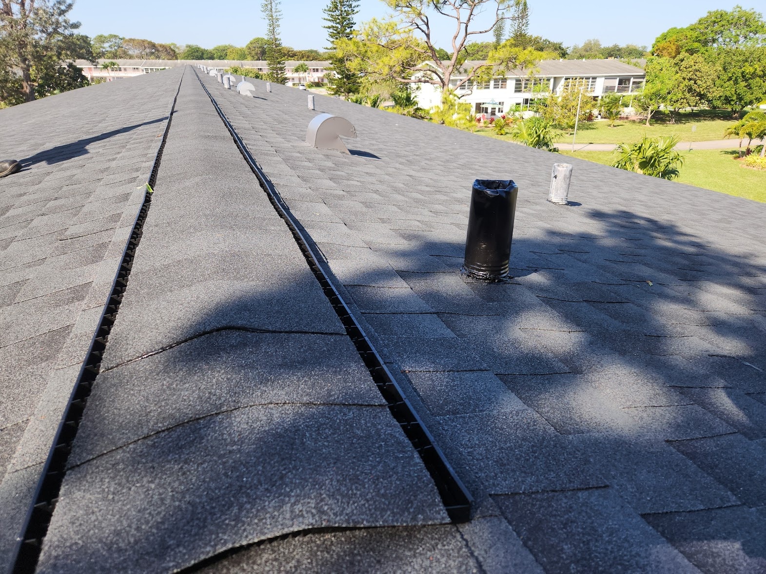 Completed gray shingle condo roof with ridge vent and pipe boots – Lyndhurst