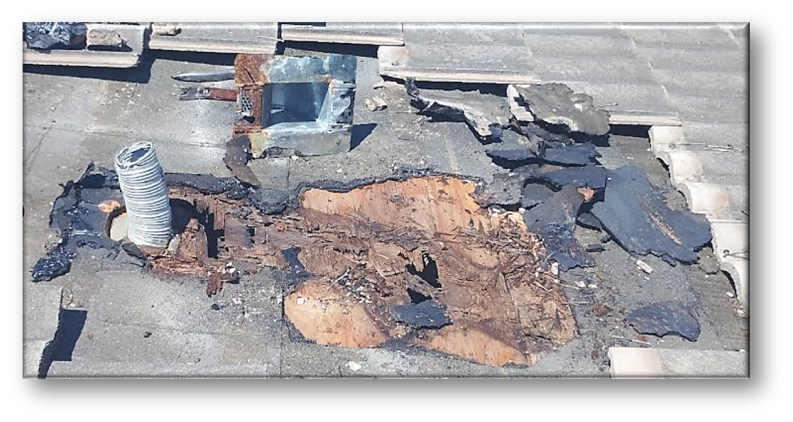 Severely deteriorated flat roof section with large rotted hole, rusted vent pipe, and broken membrane debris – Job 26-098