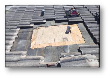 Concrete tile roof with tiles removed showing exposed plywood deck patch and circular saw – Job 26-098