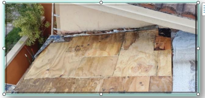 New plywood decking panels installed on concrete tile roof repair – exposed deck with fresh sheathing boards adjacent to stucco wall