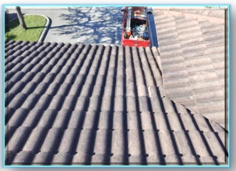 Aerial view of completed dark concrete barrel tile roof with red work truck parked alongside – finished tile roof replacement South Florida