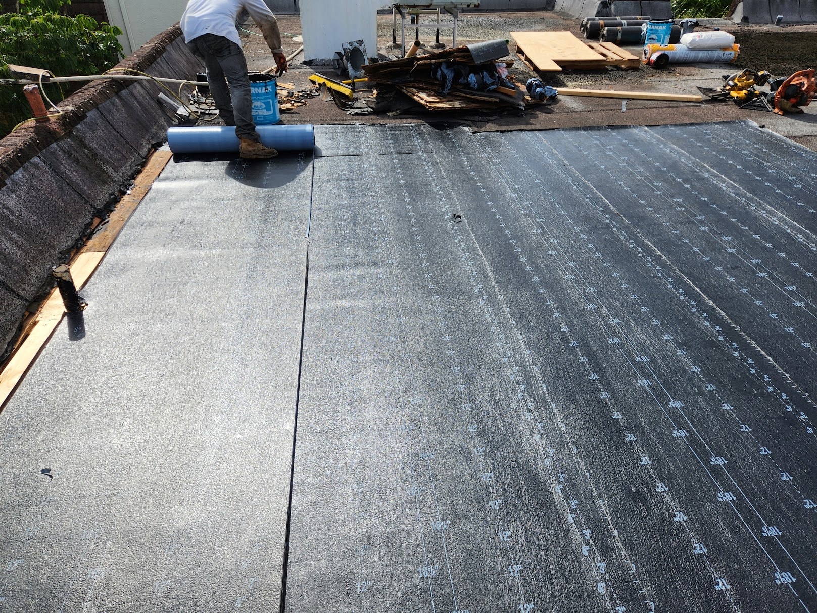 Modified bitumen membrane being rolled out during flat roof repair