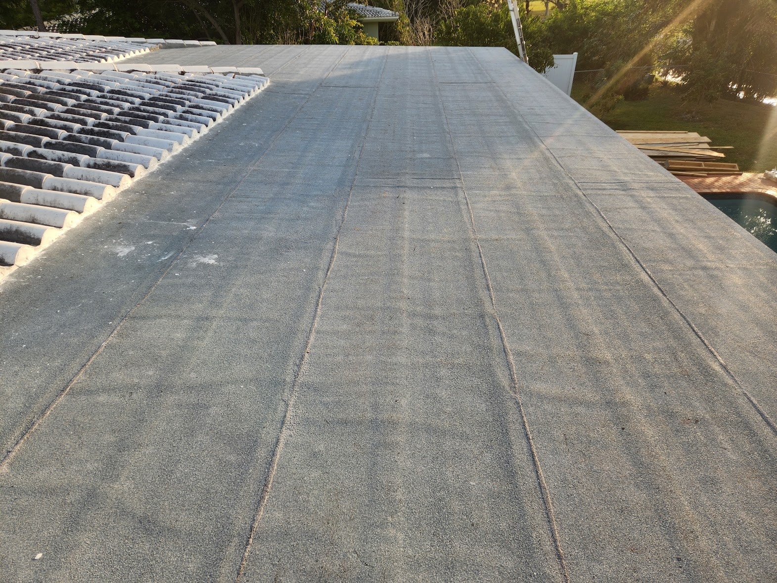 Completed flat roof with pool view at sunset – March 2025