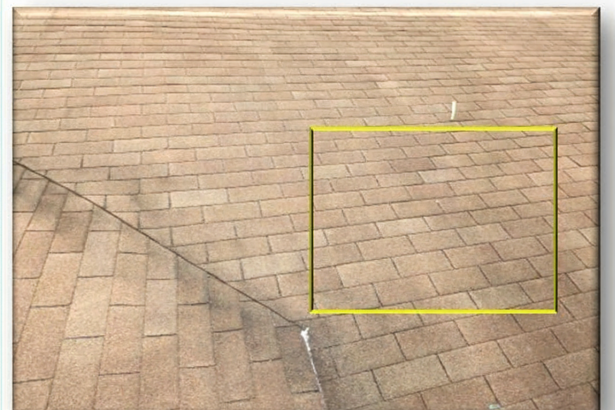 Asphalt shingle roof showing valley line and highlighted repair area with yellow box marking damaged shingles – Artisan Roof Specialists